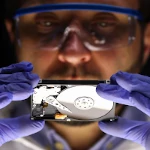 Digital forensic specialist examining a computer hard drive.