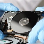 Computer technician wearing gloves working on a hard drive